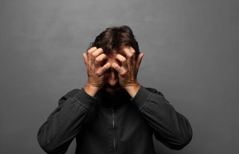 איש במתח מחזיק את הראש עם הידיים